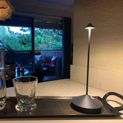 Lamp on a table with a glass and water bottle in front of a window