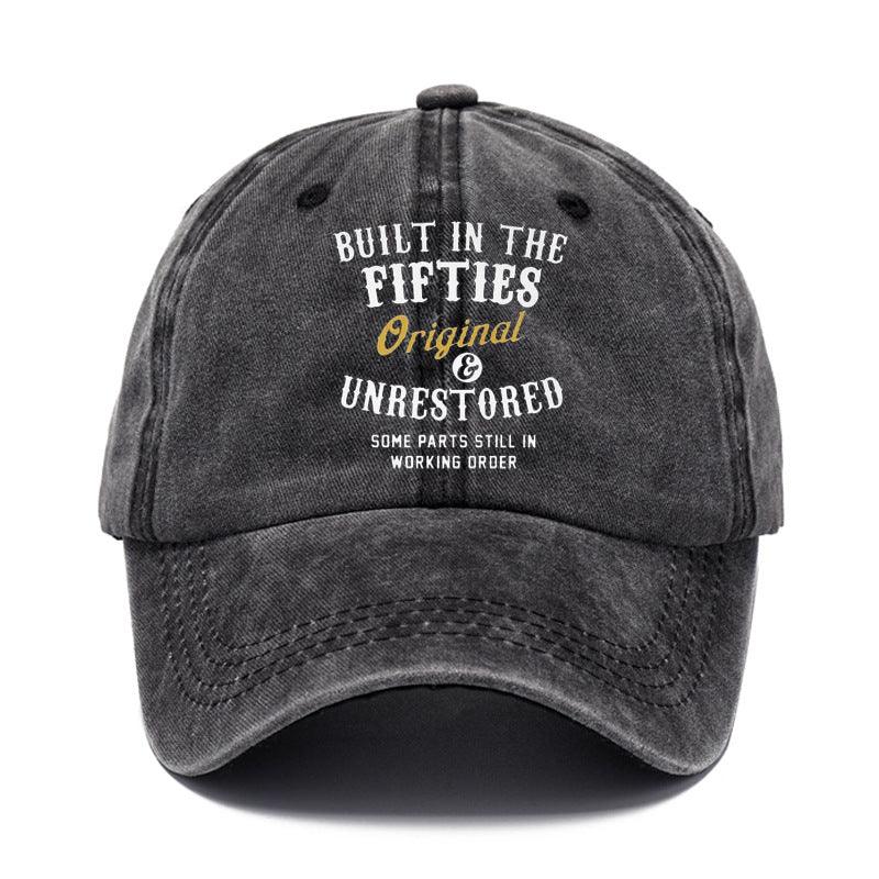 Black baseball cap with text 'Built in the Fifties, Original & Unrestored' on a white background