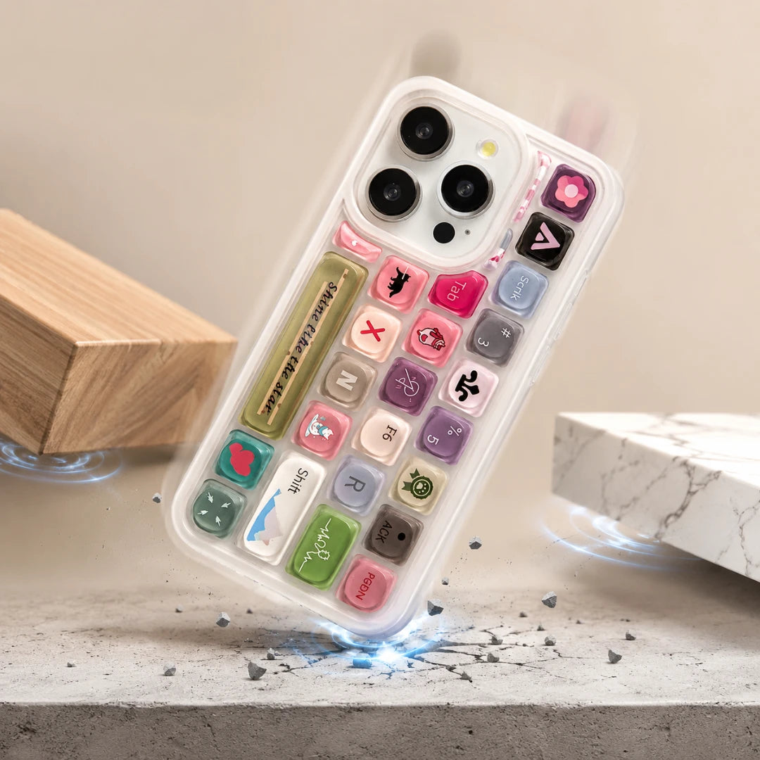 Josh & Tate - ClickPod™ Keycap Phone Case - A clear phone case with a colorful retro keypad design, shown floating above a stone surface with decorative blocks in the background.