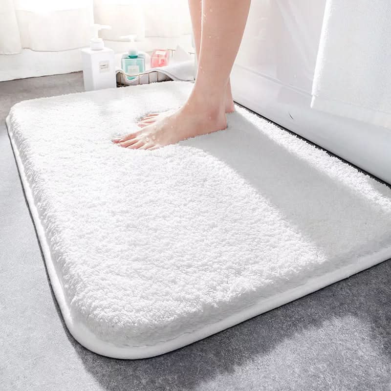 White bath mat on a bathroom floor with a foot stepping onto it