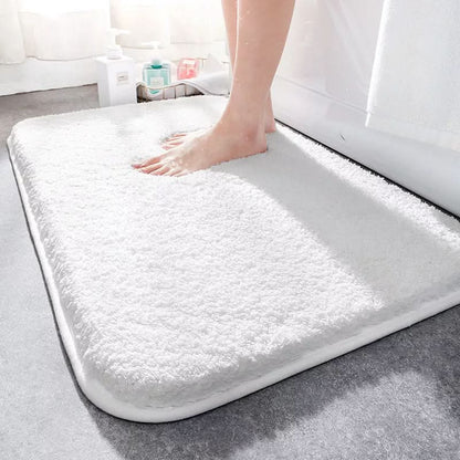 White bath mat on a bathroom floor with a foot stepping onto it