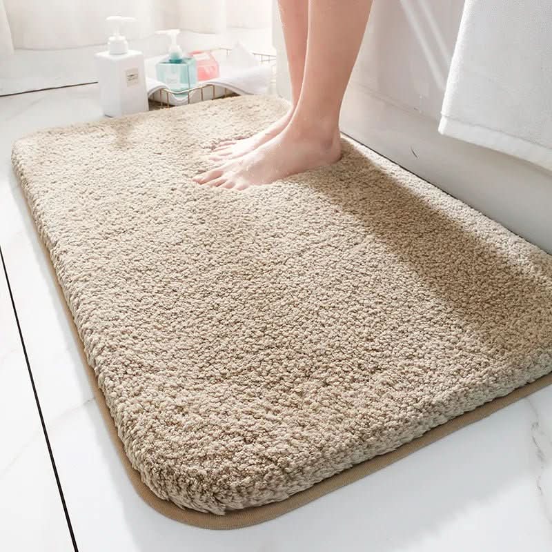 Beige bath mat on a bathroom floor with a person stepping onto it.
