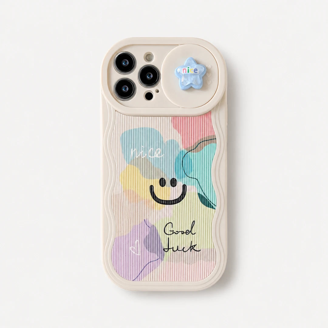 Josh & Tate - CloudPop™ Sliding Lens iPhone Case - A cream-colored phone case featuring a pastel multicolor abstract design with a smiley face and the words 'nice' and 'Good luck'. It has a small blue star charm attached to the camera ring.