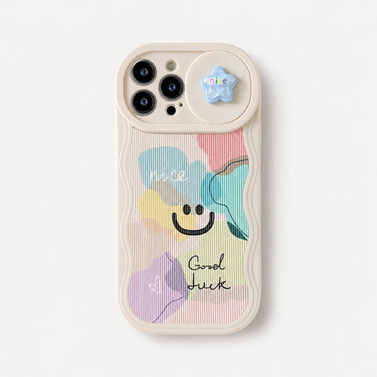 Josh & Tate - CloudPop™ Sliding Lens iPhone Case - A cream-colored phone case featuring a pastel multicolor abstract design with a smiley face and the words 'nice' and 'Good luck'. It has a small blue star charm attached to the camera ring.