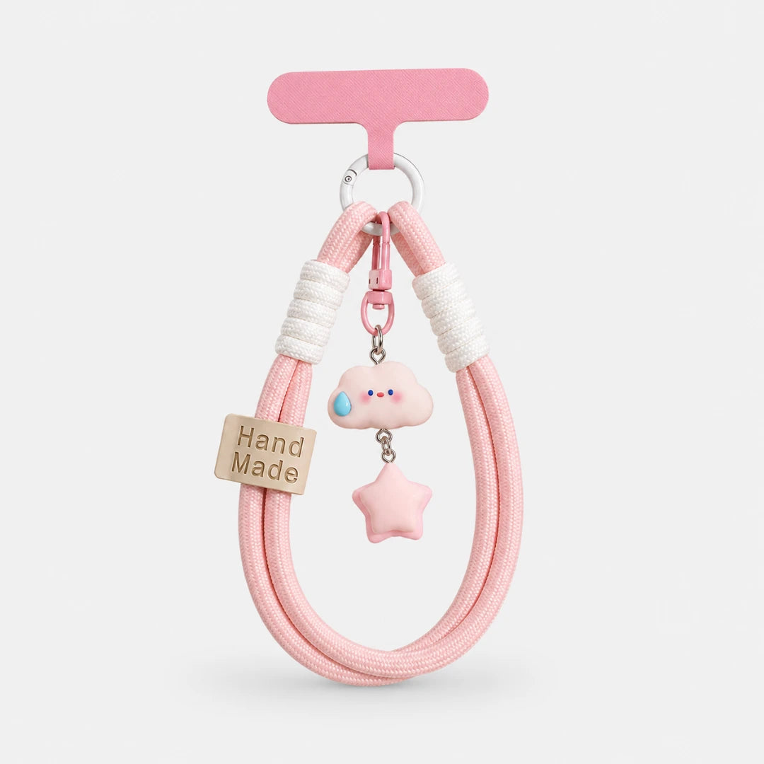 Josh & Tate - CloudStar™ Phone Lanyard - A pink braided cord accessory with a pink T-shaped hanger, featuring a small pink cloud charm with a blue tear drop, a pink star charm, white ribbed bands, and a wooden tag that reads 'Hand Made' on a light gray background.