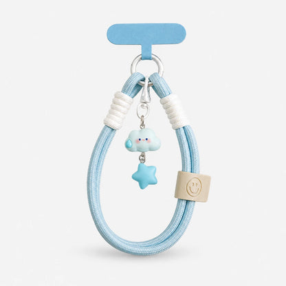 Josh & Tate - CloudStar™ Phone Lanyard - A light blue braided hair tie with white ribbed accents, a small blue cloud charm, a blue star charm, and a beige square tag with a smiley face, displayed on a light gray background.