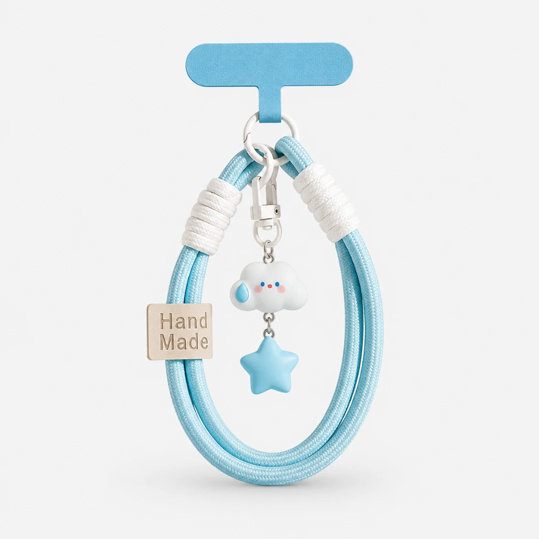 Josh & Tate - CloudStar™ Phone Lanyard - A light blue braided hair tie with white wrapped ends, a small white cloud charm with blue eyes, a light blue star charm, and a beige 'Hand Made' tag, displayed on a light gray background.