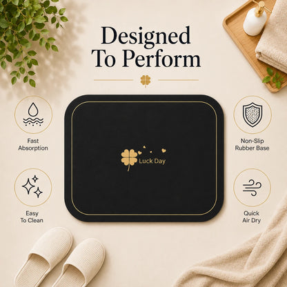 Josh & Tate - CloverDry™ Diatomite Bath Mat - Black mat with 'Luck Day' logo on a beige surface, surrounded by text and icons about product features.