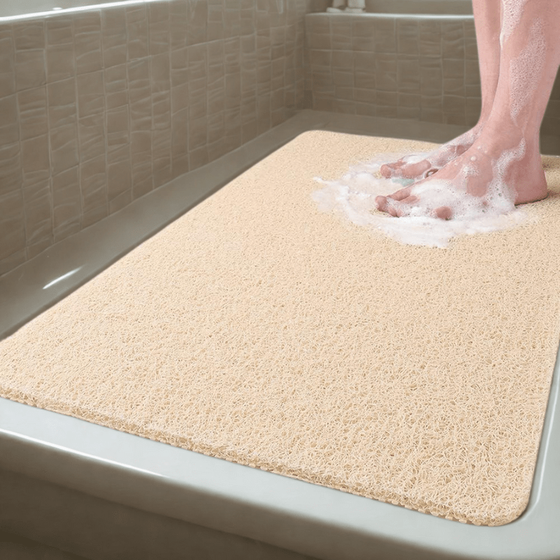 Beige bath mat on a bathtub with soapy feet stepping onto it