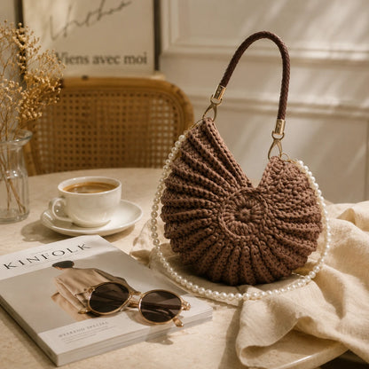 Josh & Tate - ConchKnit™ Pearl Handbag - Brown knitted handbag on a table with a cup of coffee, sunglasses, and a book.