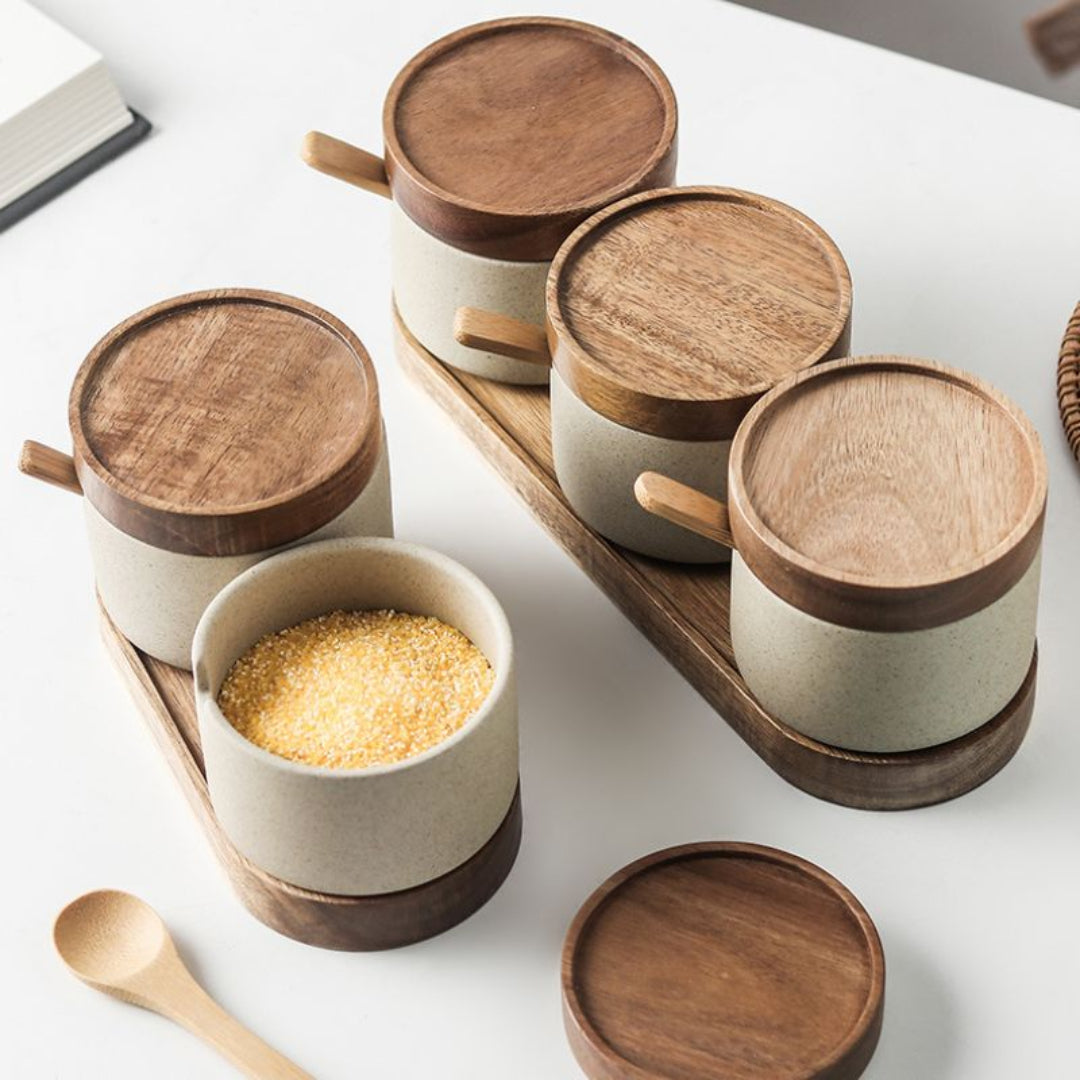Set of wooden and ceramic containers with a wooden spoon on a white surface