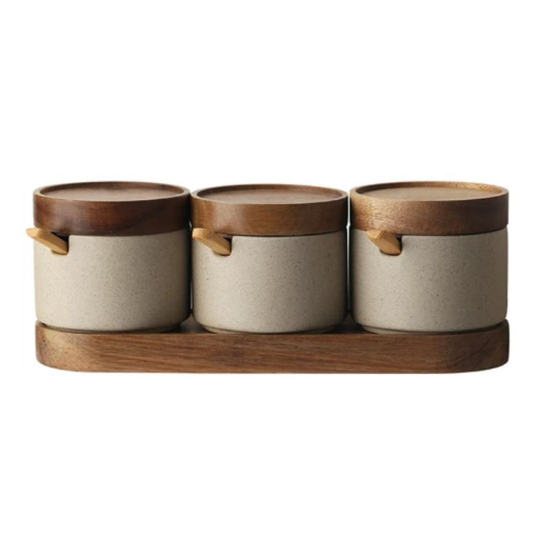 Three ceramic containers with wooden lids on a wooden stand against a white background