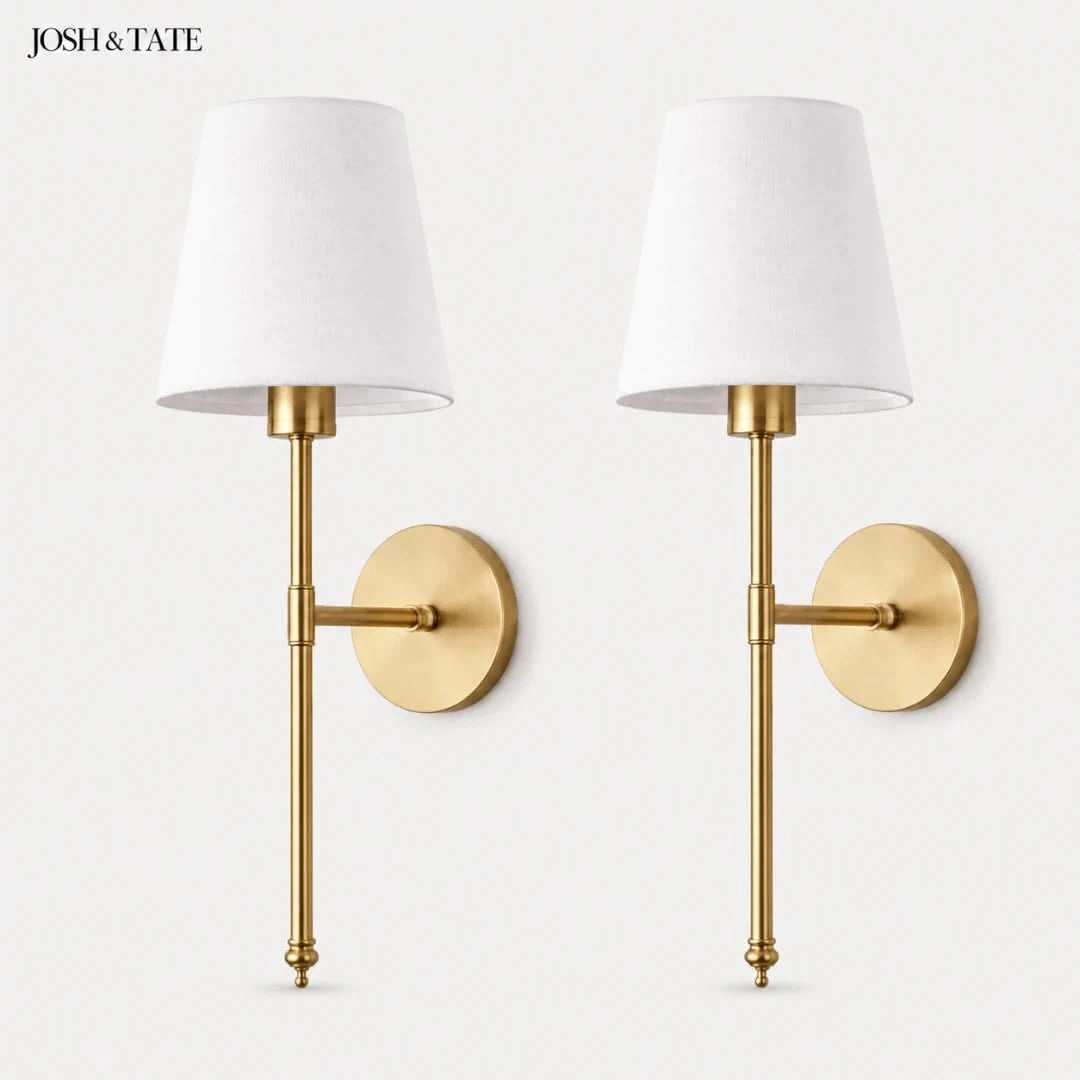Josh & Tate - Cordless Fabric Wall Light - Two gold wall sconces with white lampshades on a light gray background, featuring the brand 'Josh & Tate'.