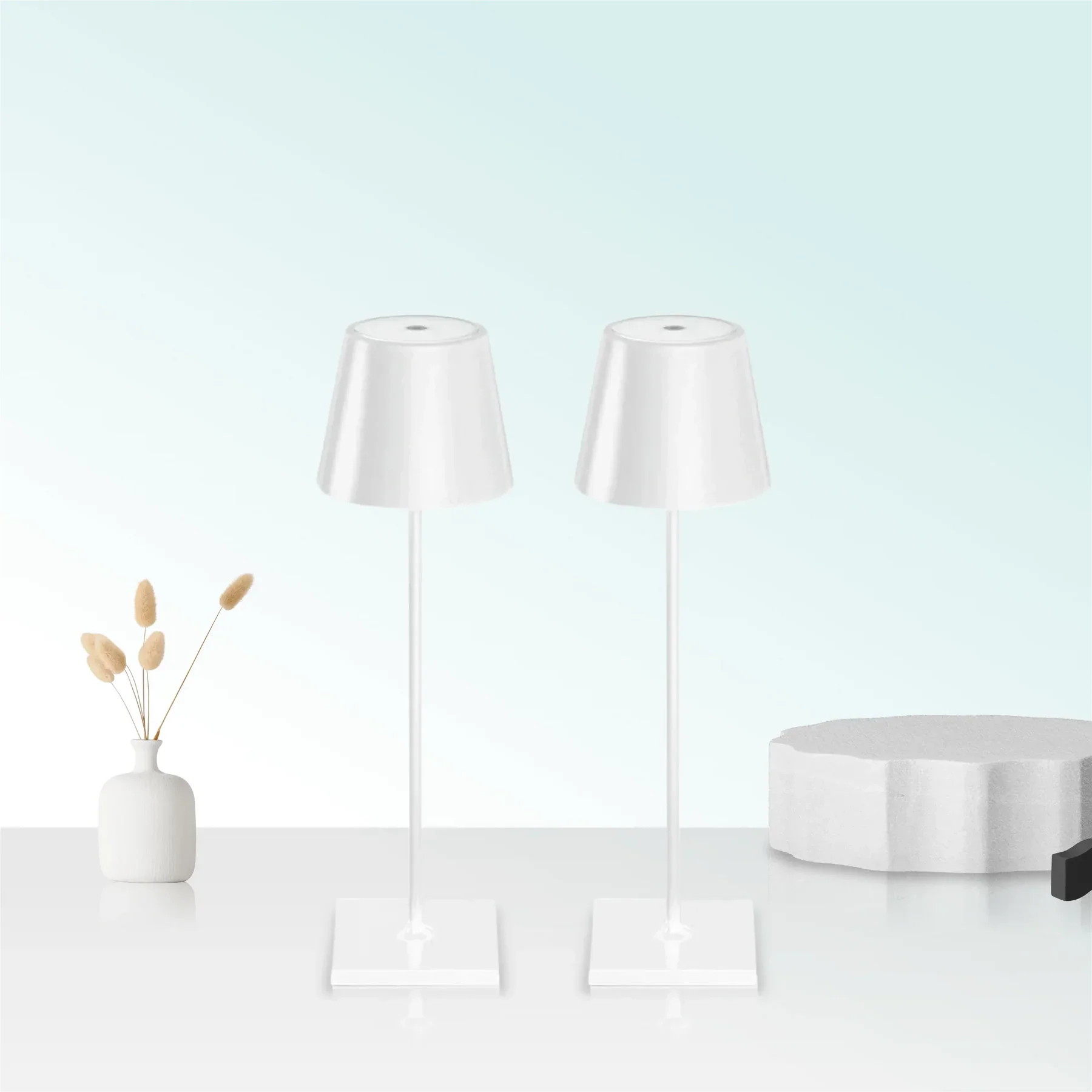 Two white lamps on a white surface with a light blue background