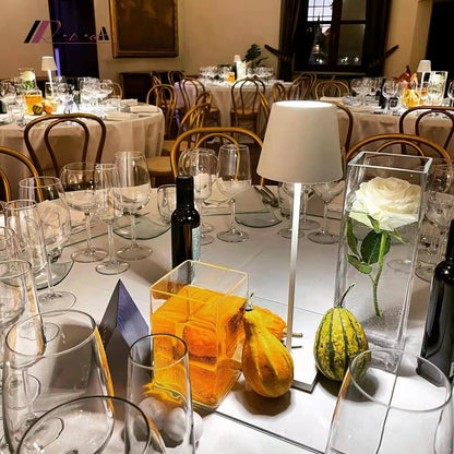 Elegant dining room with tables set for a formal event, featuring glassware, flowers, and decorative items.