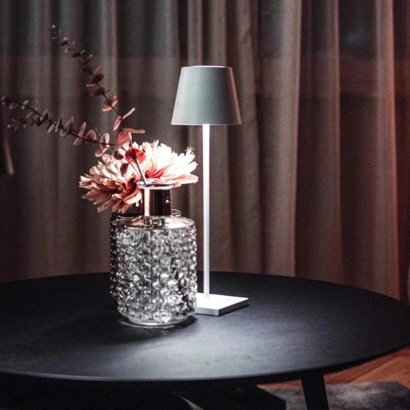 Decorative lamp with floral arrangement on a table against a curtain backdrop