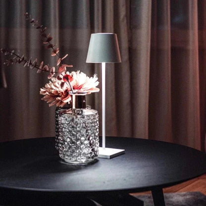 Decorative lamp with floral arrangement on a table against a curtain backdrop