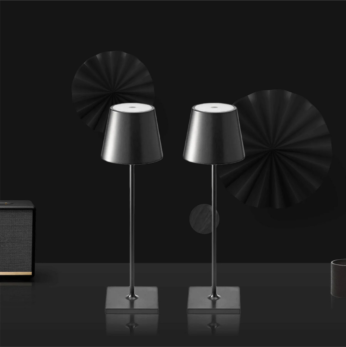 Two black table lamps on a reflective surface with a dark background