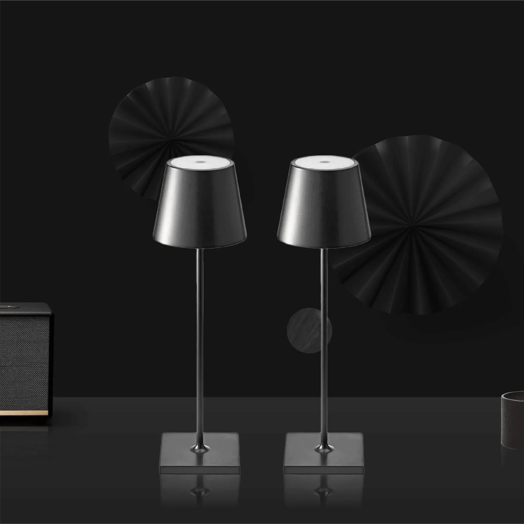 Two black table lamps on a reflective surface with a dark background