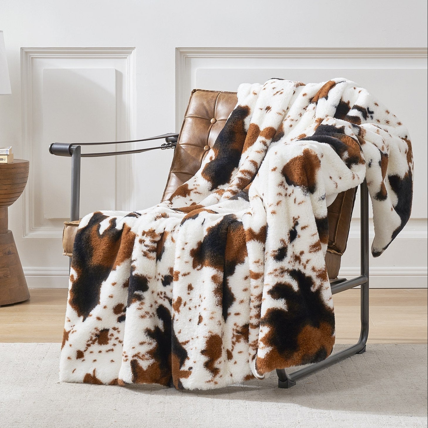 Brown and white patterned blanket draped over a brown leather chair in a room with light-colored walls and flooring.