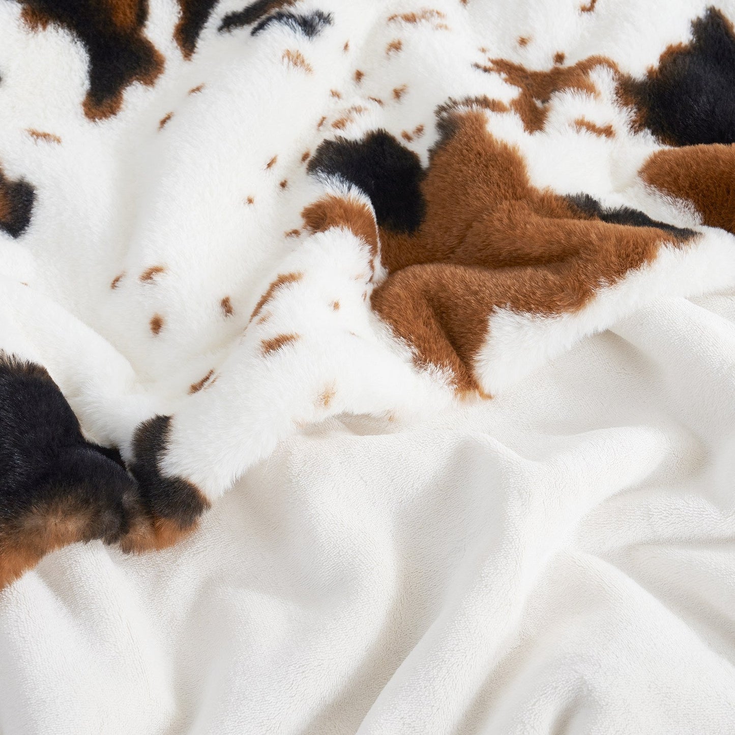 Close-up of a cowhide rug with brown and black patches on a white background