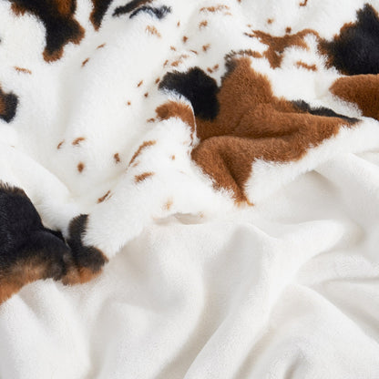 Close-up of a cowhide rug with brown and black patches on a white background