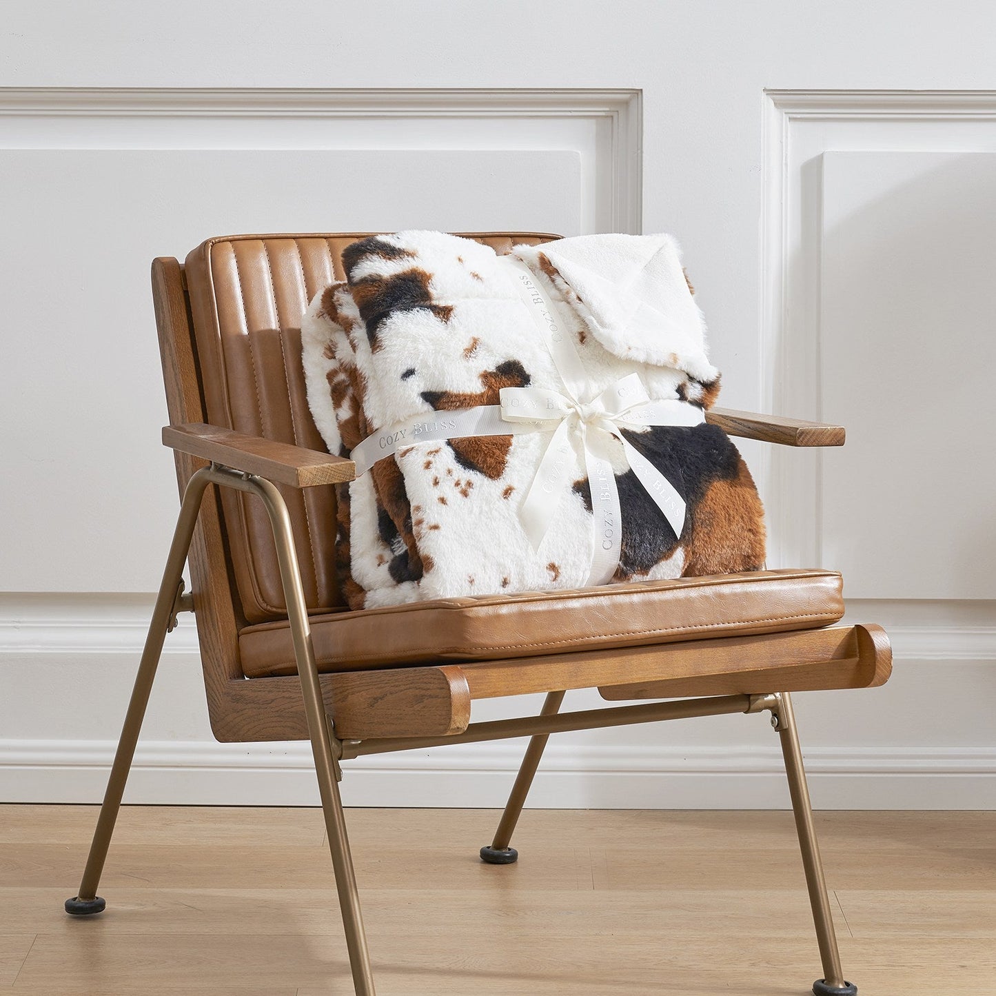 Wooden chair with a blanket and stuffed animal on a light wooden floor.