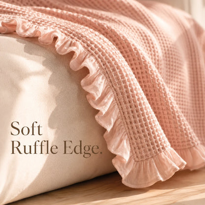 Josh & Tate - CozyCradle™ Ruffle-Edge Cotton Bed Blanket - Pink textured blanket with ruffle edge on a wooden surface