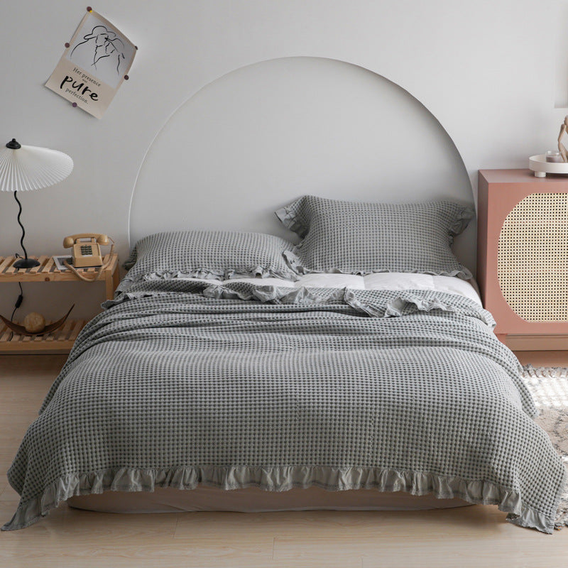 Josh & Tate - CozyCradle™ Ruffle-Edge Cotton Bed Blanket - Bedroom with a bed featuring gray checkered bedding, nightstands, and decor items.