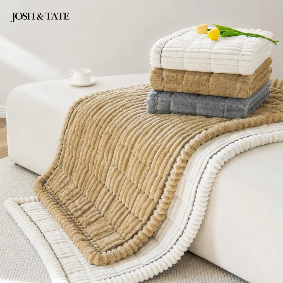 Josh & Tate - CozyLayer™ Plush Sofa Protector - Stack of folded towels on a couch with 'Josh & Tate' branding.