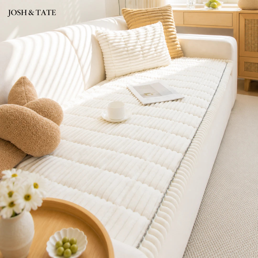 Josh & Tate - CozyLayer™ Plush Sofa Protector - White mattress cover on a bed with decorative pillows and a small table in a room.