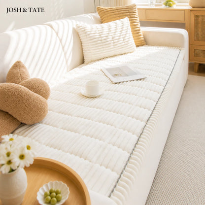 Josh & Tate - CozyLayer™ Plush Sofa Protector - White mattress cover on a bed with decorative pillows and a small table in a room.