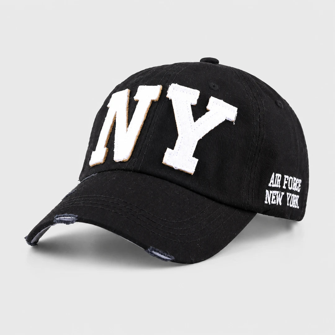 Josh & Tate - CraftWorn™ Distressed NY Cap - A black distressed baseball cap featuring large white embroidered 'NY' letters on the front with a thin gold outline, and 'AIR FORCE NEW YORK' embroidered in white on the side, shown against a light gray background.