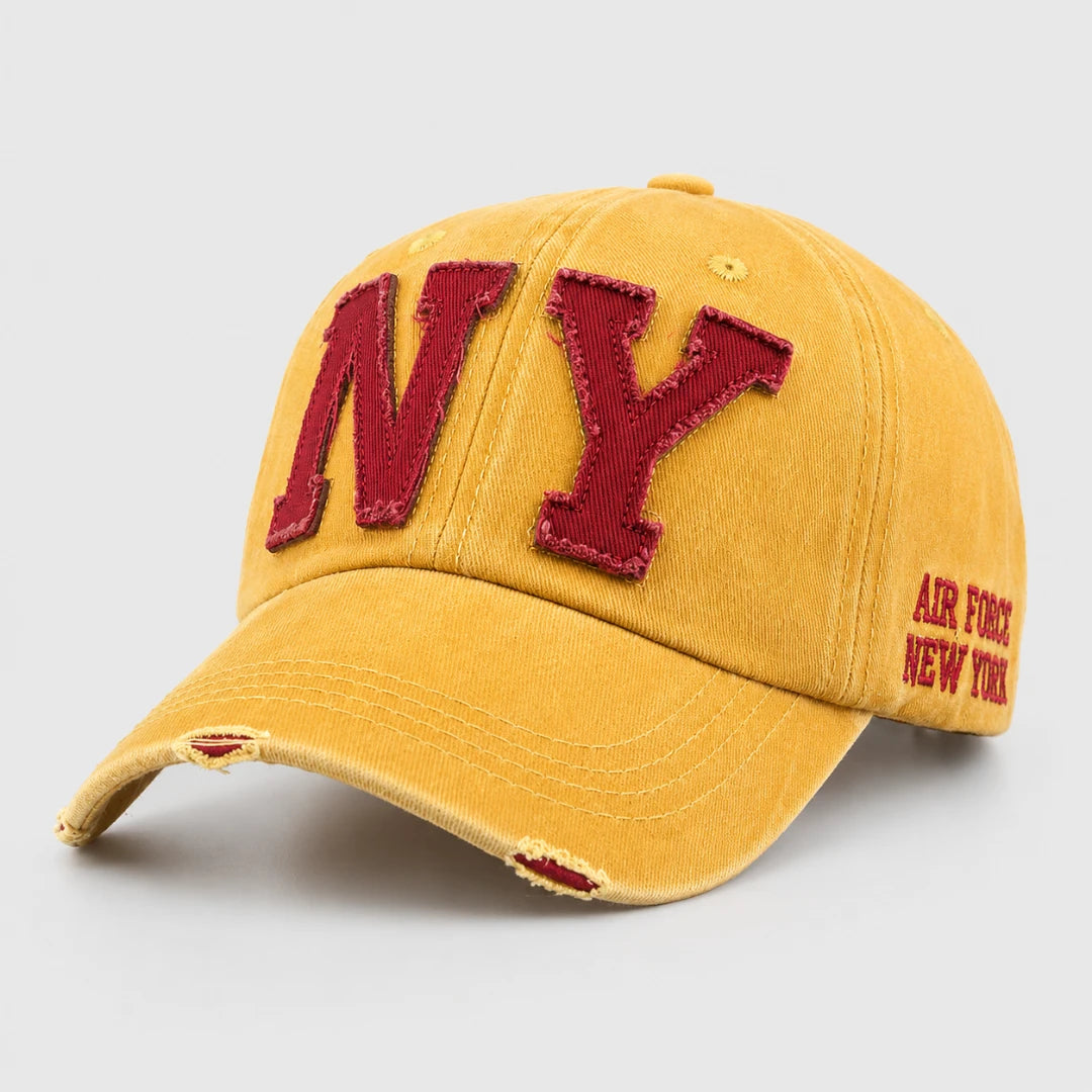 Josh & Tate - CraftWorn™ Distressed NY Cap - A yellow distressed baseball cap with a red embroidered 'NY' on the front and 'AIR FORCE NEW YORK' on the side, shown on a light gray background.