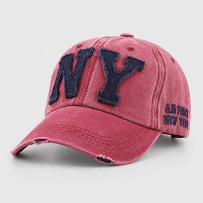 Josh & Tate - CraftWorn™ Distressed NY Cap - A distressed pink baseball cap with dark navy blue embroidered 'NY' lettering on the front and 'AIR FORCE NEW YORK' text on the side, shown on a light gray background.