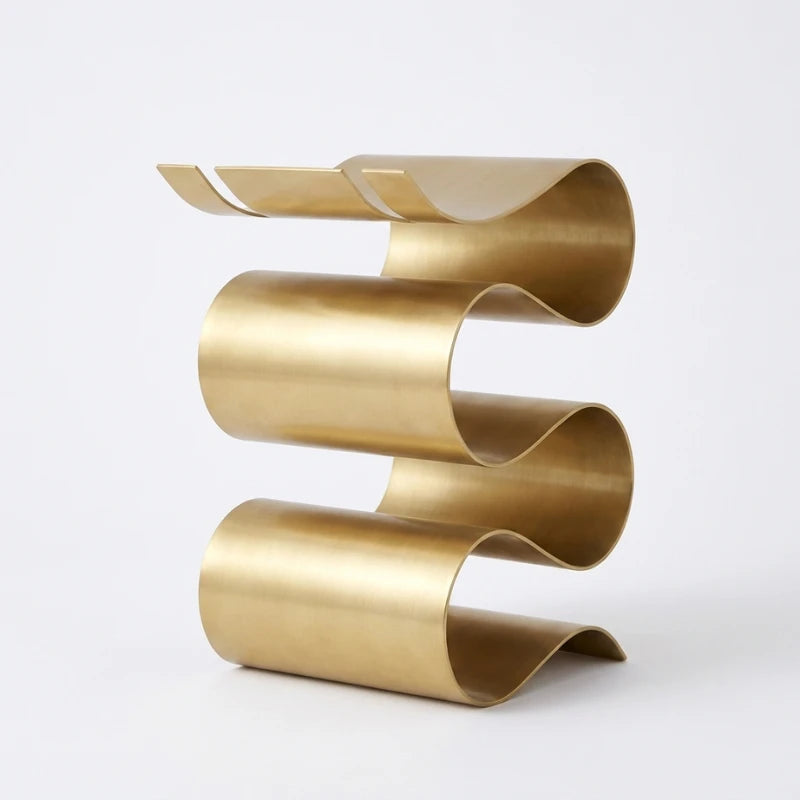 Gold metal side table with wavy design on a white background