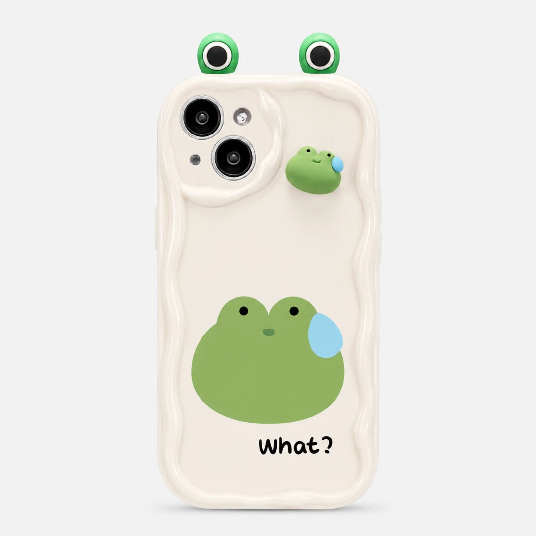 Josh & Tate - CuteSilicone™ iPhone Case - A white phone case with a wavy border and cartoon frog designs. The case features a large green frog face with a blue teardrop on the back, smaller frog graphics near the camera cutout and top edge, and the word 'What?' printed in black near the bottom.