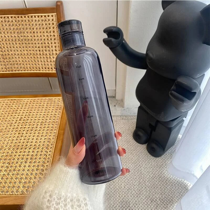 Josh & Tate - Daily Water Tracker Bottle - Person holding a clear water bottle with a black bear figurine in the background