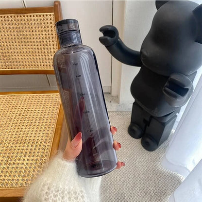Josh & Tate - Daily Water Tracker Bottle - Person holding a clear water bottle with a black bear figurine in the background