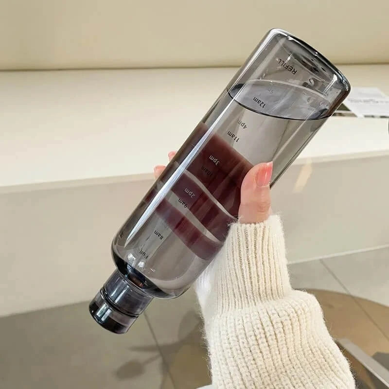 Josh & Tate - Daily Water Tracker Bottle - Clear water bottle with measurement markings held by a person wearing a white sweater.