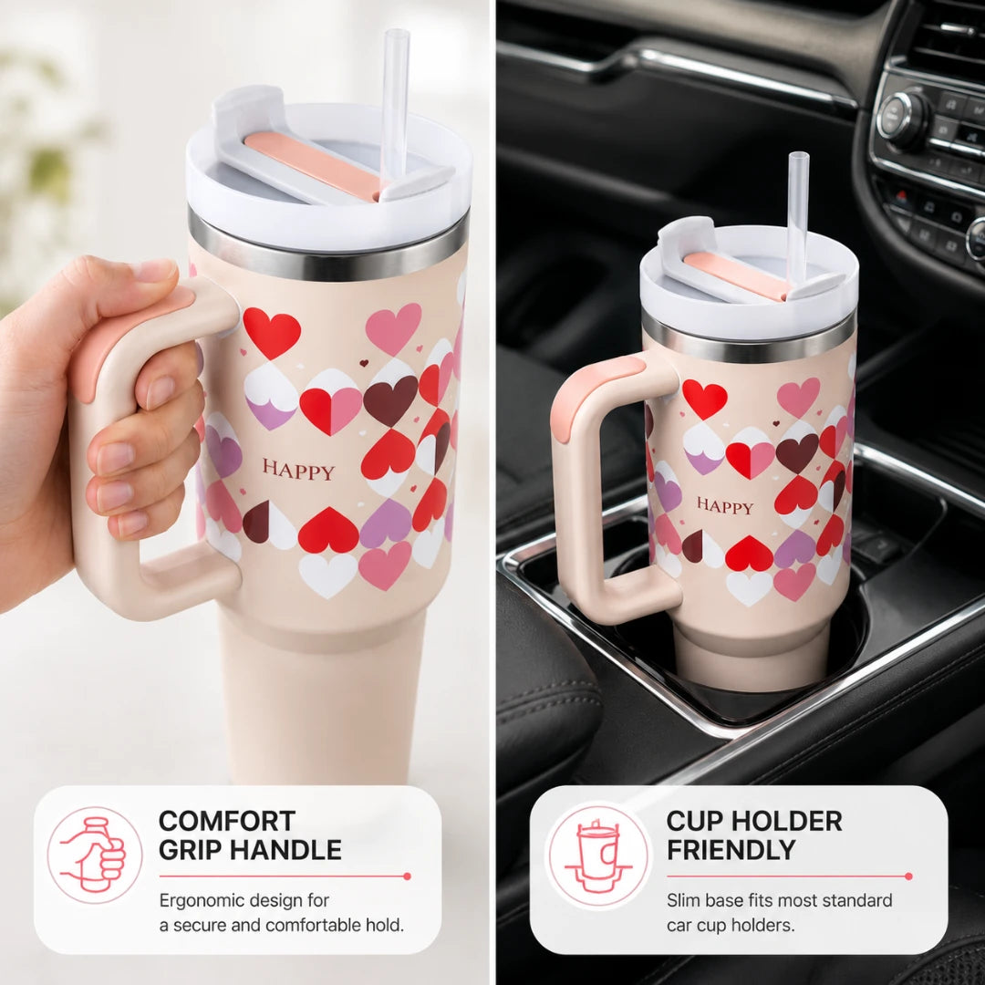 A tall insulated tumbler with a handle and straw, shown in two settings: held by a hand on the left and placed in a car cup holder on the right. The tumbler is light blush pink with a pattern of red, pink, and white hearts, and the word HAPPY printed on the front.