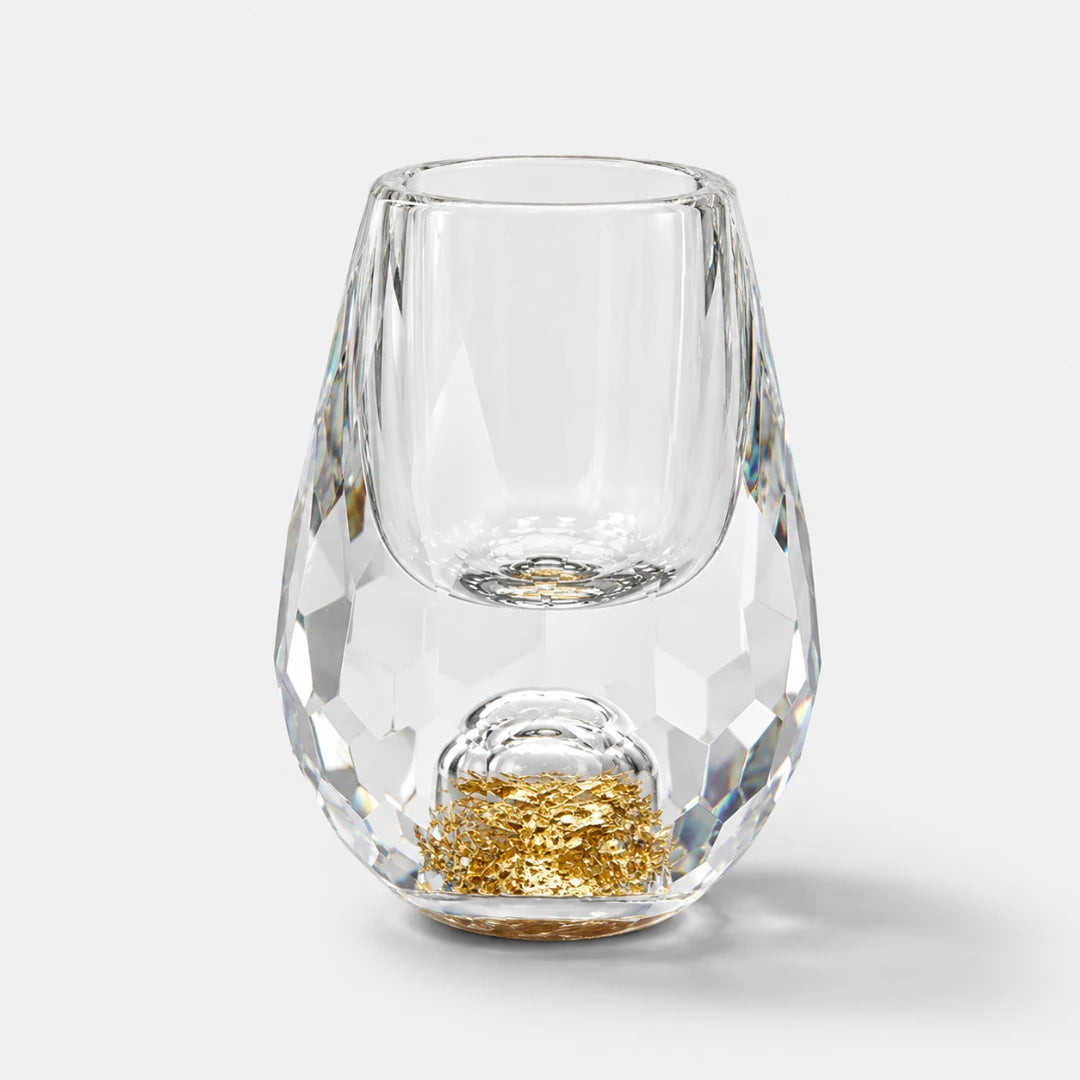 Josh & Tate - DiamondCrystal™ Shot Glass - A clear faceted stemless wine glass with a gold glitter accent at the base, photographed on a light gray background.