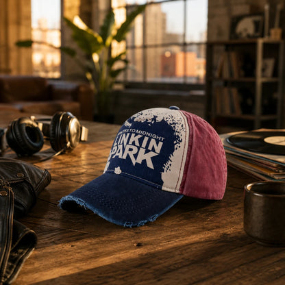 Josh & Tate - DistressedCap™ Embroidered Baseball Cap - A distressed baseball cap with a blue brim and blue front panel, white side panels, and pink back panels, resting on a wooden table in a warm, dimly lit room with headphones, records, and a mug nearby.
