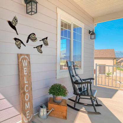 Front porch with rocking chair, decorative birds, 'Welcome' sign, and potted plant.