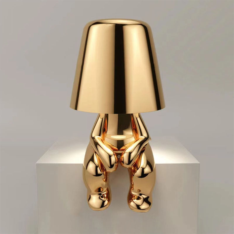 Gold-colored lamp with a unique design on a white platform against a gray background