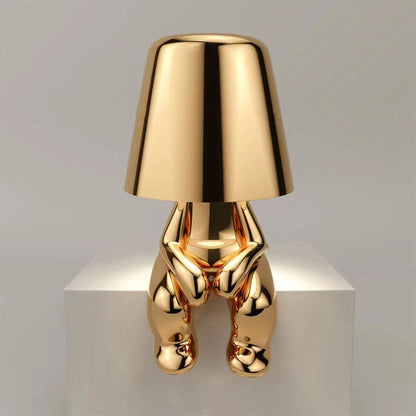 Gold-colored lamp with a unique design on a white platform against a gray background