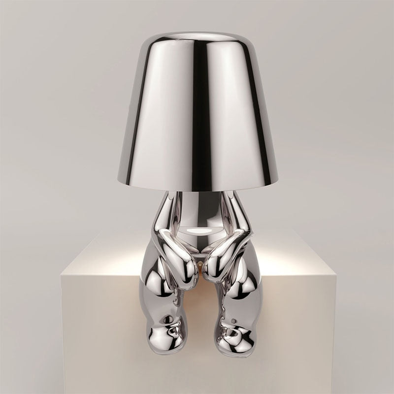 Silver lamp with a unique design on a white pedestal against a light gray background