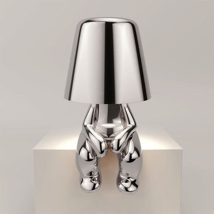 Silver lamp with a unique design on a white pedestal against a light gray background