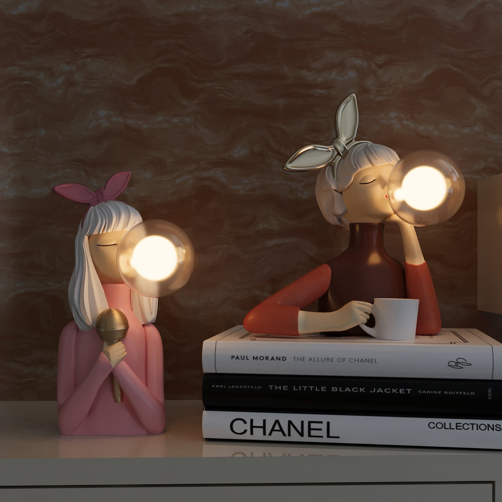 Two decorative figurines with lights on a surface with books in the background