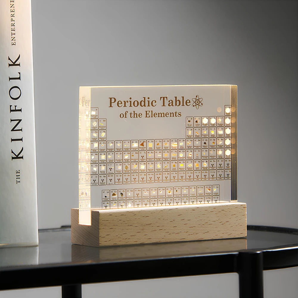 Josh & Tate - Elementa Periodic Table - Light-up periodic table of elements on a wooden base with a book titled 'KINFOLK' in the background.
